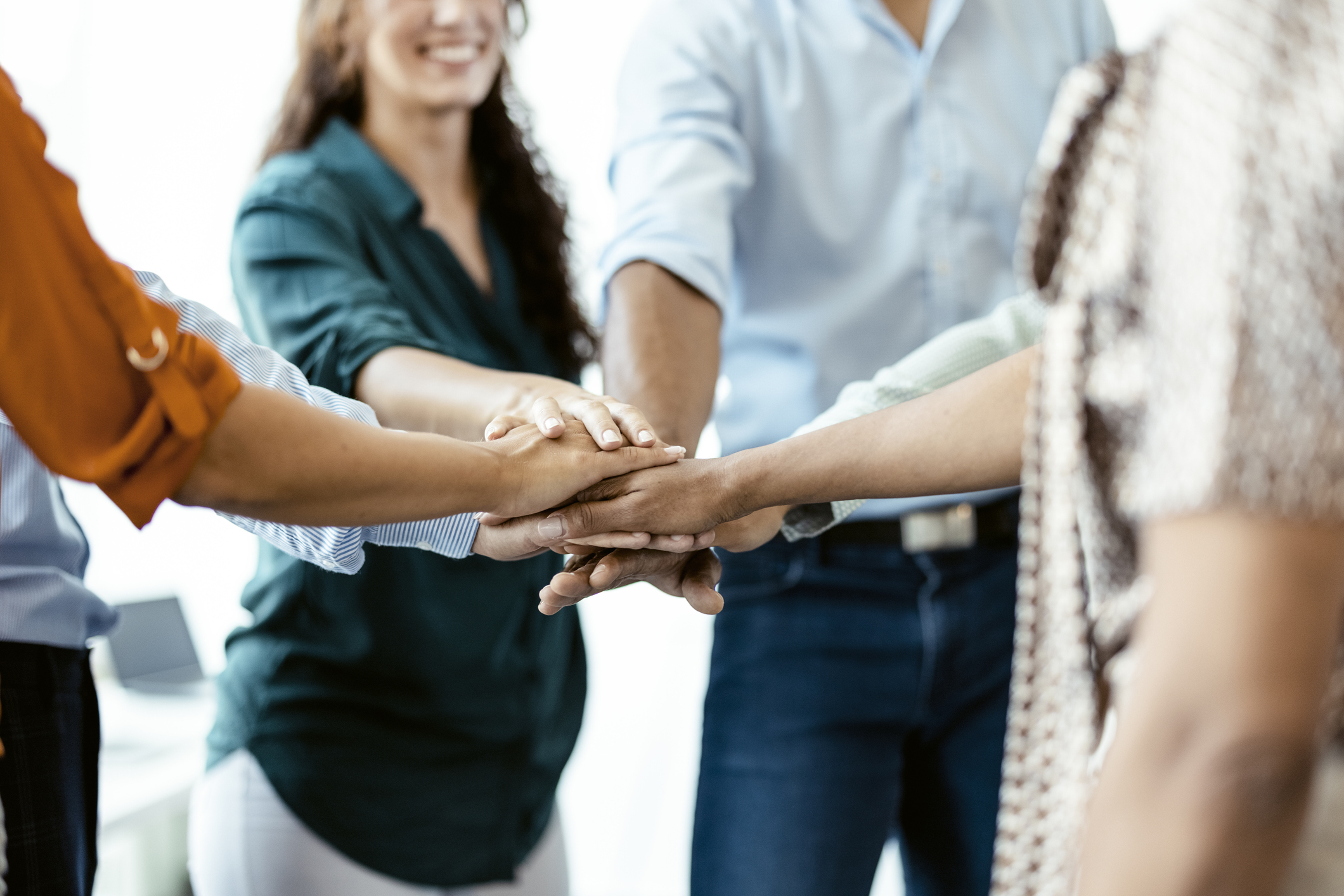 A group of people joining hands in a circle as part of team building.
