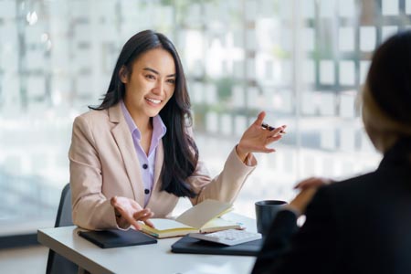 A female manager conducting an interview at a table in an office for a job opening.