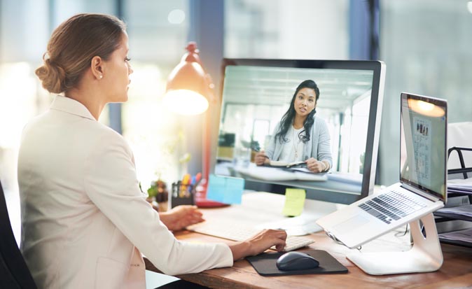 A female hiring manager in her office on a video call with a job applicant shown on computer screen.
