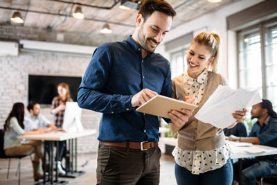 A man and woman in an office looking at a piece of paper.