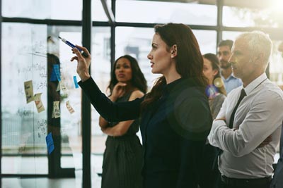 A group of business people standing in front of a glass wall, discussing strategic planning.