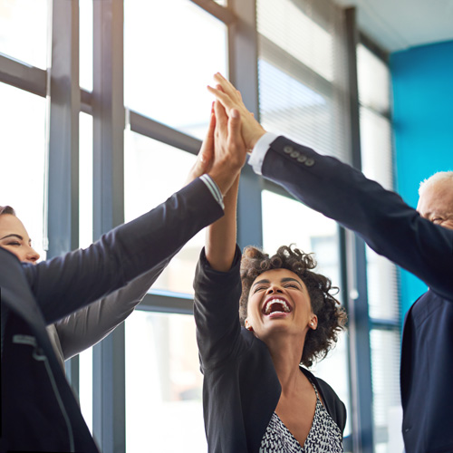 A group of managers smiling and giving each other a high five.