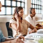 A group of people working in a call center with headsets on.